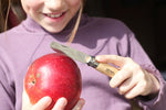 Enfant qui coupe une pomme avec le couteau mon premier Opinel