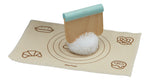 Jeux d'imitation en bois et tissu pour enfant representant un atelier à pain, il est composé d'un tapis à patissier avec posé dessus un pompon blan en laine et un découpe pâte qui coupe le pompon