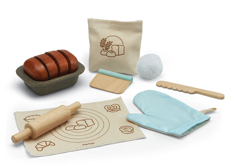 Jeux d'imitation en bois et tissu pour enfant representant un atelier à pain, il est composé d'un tapis à patissier, un rouleau à patissier un gant de cuisine, un couteau en bois, un découpe pâte en bois, un moule à cake avec un pain à l'intérieur et un sachet de farine en tissus