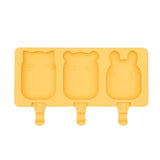 Frosties Moule à glace en silicone de couleur jaune, il represente 3 petits moules en forme d'animaux : chat, panda et lapin. Il y a des encoches en dessous de chaque moule pour y insérer des bâtonnets à glace 