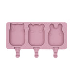 Frosties Moule à glace en silicone de couleur rose, il represente 3 petits moules en forme d'animaux : chat, panda et lapin. Il y a des encoches en dessous de chaque moule pour y insérer des bâtonnets à glace 