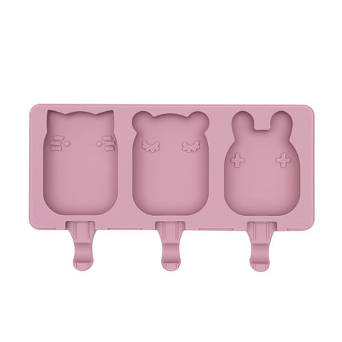 Frosties Moule à glace en silicone de couleur rose, il represente 3 petits moules en forme d'animaux : chat, panda et lapin. Il y a des encoches en dessous de chaque moule pour y insérer des bâtonnets à glace 