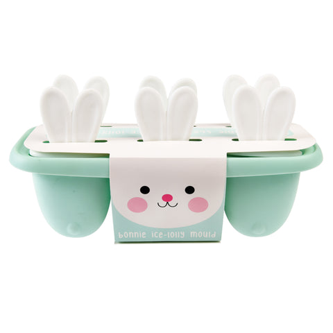 Moule à glace Bonnie le lapin avec son emballage sur fond blanc. Le moule a la base vert d'eau, et les manche blanc en forme d'oreilles de lapin. Il y a 6 espaces à glaces
