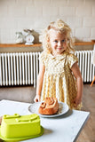 Photo d'une petite fille blonde qui sourire dans une cuisine avec posé devant elle un gâteau en forme de tête de crocodile 