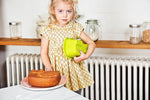 Photo d'une petite fille blonde aux yeux bleu qui porte sous son bras un moule en silicone vert. devant elle est posé dans une assiette un gateau en forme de tête de crocodile