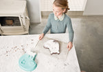 Photo d'une jeune fille dans une cuisine qui porte dans ses mains une grille de cuisson avec dessus un gâteau au chocolat. Sur la table devant est posé un moule en forme de tête d'ours