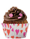 Muffins au chocolat avec une crème au chocolat sur le dessus et des perle de sucre roses, le gateau est dans un moule a muffin avec des motifs coeurs
