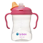 Tasse pour enfant avec sa base transparente et son couvercle avec poignée de couleur rose. il y a une petit bec transparent et son couvercle amovible de couleur orange