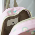 Gros plan sur l'intérieur d'un sac à dos pour enfant de couleur rose avec motif arbre. La fermeture et la hanse sont de couleur kaki. La marque du sac indiqué sur l'étiquette a l'intérieur est maison Petit Jour