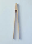 Photo d'une pince à toast en bois, la pince est posée sur un fond blanc