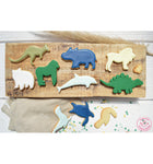 Biscuit en forme dd'animaux décoré avec de la pate à sucre. ils sont posé sur une planche en bois et une table avec des confettis