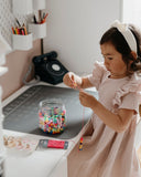 Photo d'une jeune fille qui est assise devant une table et qui fait une activité avec des perles