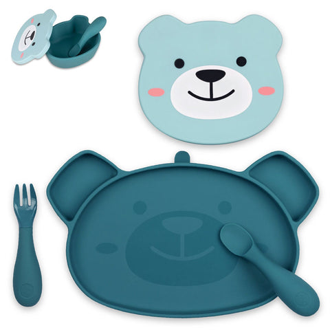 Set de repas pour enfant composé de plusieurs éléments. Le tout est posé sur un fond blanc. Il y a en avant plan une assiette compartimentée en silicone de couleur bleu, l’assiette à une forme d’ours. Une cuillère et une fourchette de la même couleur sont posés dans et à côté de l’assiette. Au dessus de l’assiette, le couvercle d’un bol de couleur bleu et de forme de tête d’ours avec des illustrations coloré. Sur le côté gauche un bol de la même couleur et de forme de tête d’ours.