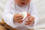 Gros plan sur un bébé qui tient dans les main un jouet en forme de champignon blanc et rouge