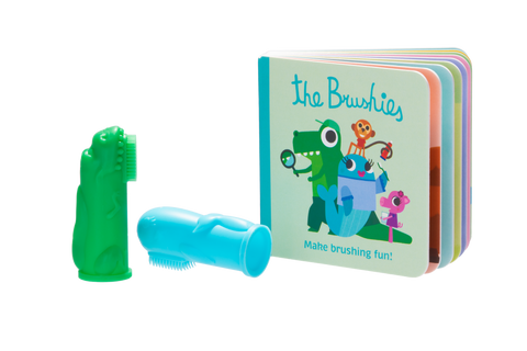 Photo sur fond transparant de 2 brossettes a dents en silicone de couleur verte et bleue avec à coté un petit livre en carton avec comme titre The Bruchies