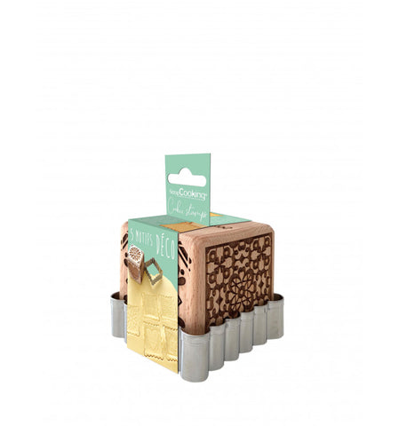 Photo d'un emballage contenant un decoupoir en inox pour biscuit avec à l'ntérieur un tampon en bois en forme de carré. Le tampon est gravé et représente des motifs pour Noêl