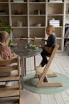 2 jeunes enfants entrain de manger à table.  Ils sont dans une salle à manger au style scandinave. La vaisselle devant eux est de couleur neutre