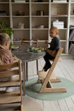 2 jeunes enfants entrain de manger à table.  Ils sont dans une salle à manger au style scandinave. La vaisselle devant eux est de couleur neutre