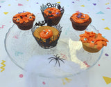 Cupcakes d'halloween posés sur un plateaux. Ils sont décorés avec un glaçage de couleurs oranges et des décors en sucre avec des yeux, tête de mort et os d'halloween