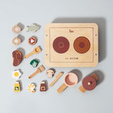 Photo d'une dinette en bois. pour enfant. il y a un rechaud en bois avec posé dessus des casseroles avec des ingrédients et des sauces